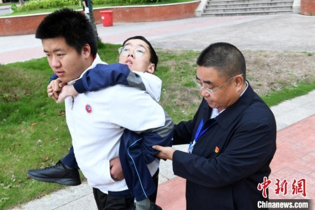 朱金祥背着钟华强去教室上课的路上，也经常碰到值班的校领导和老师前来搭把手。　 卓忠伟 　摄