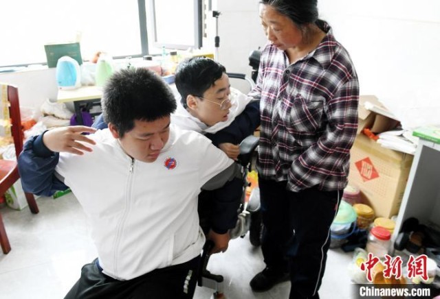 江西省南康中学北校区的高三学生朱金祥(左)来到学校给钟华强母子安排的公寓，准备背他去课堂上课。　 卓忠伟 　摄